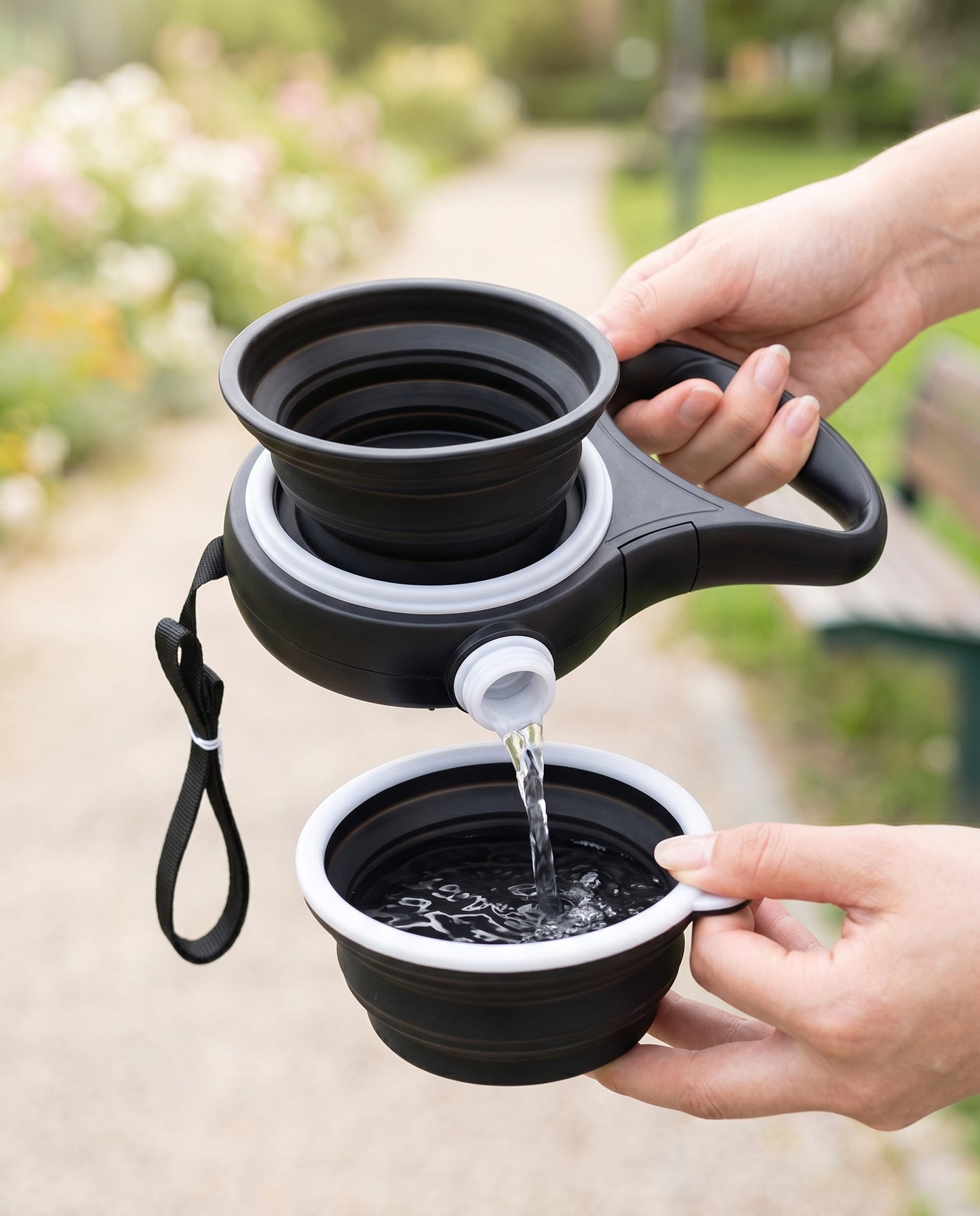 Hands popping open the collapsible silicone bowl and pouring water from the Joobello walking water bottle dog leash