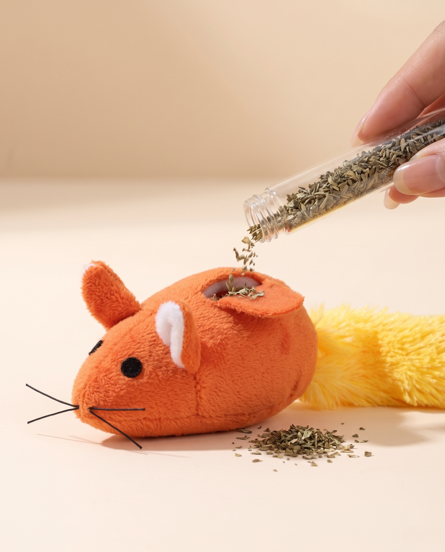 Refilling catnip into the Joobello plush mouse toy from its refillable catnip tube