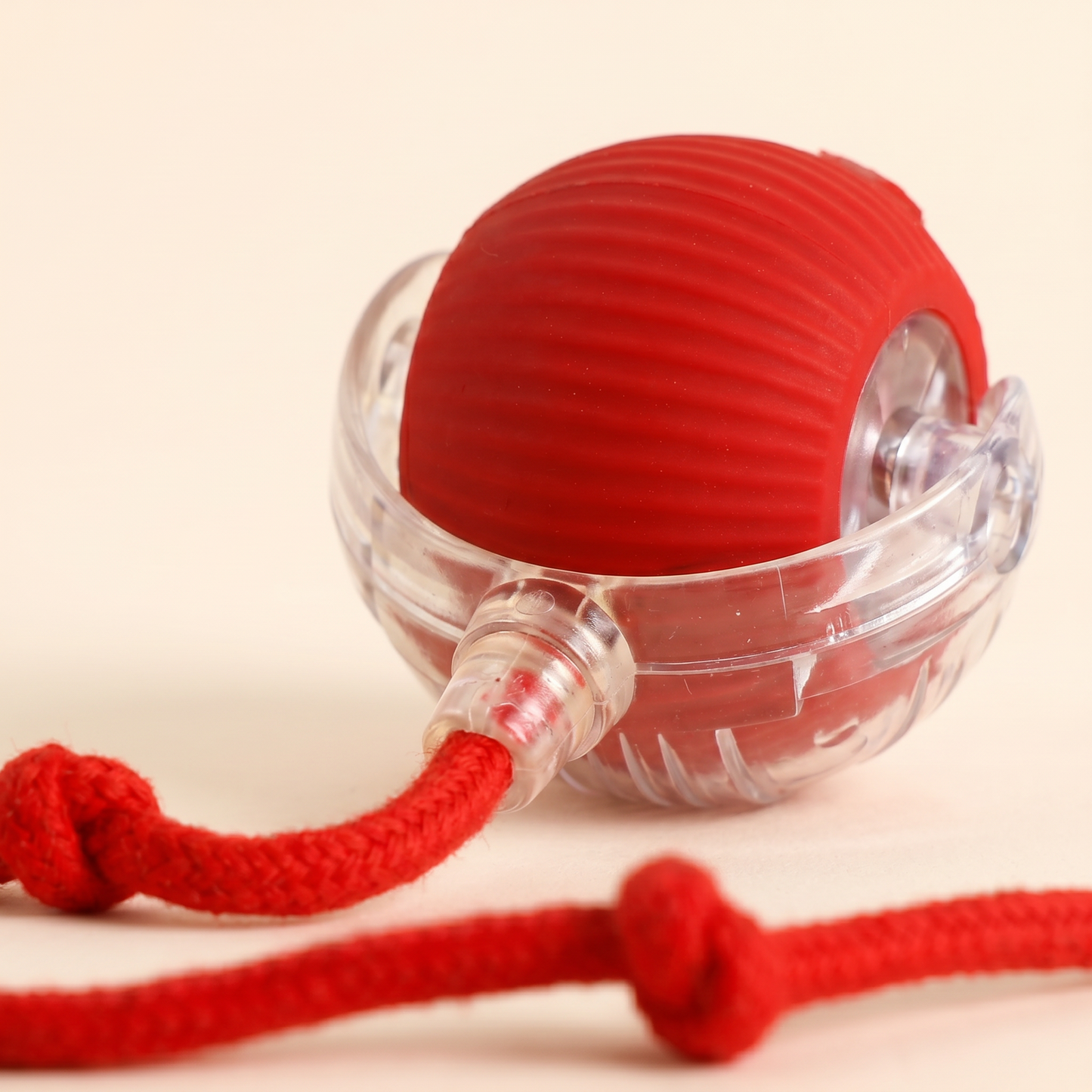 Macro of the Joobello smart rolling pet ball red silicone core inside the clear shell and rope tail